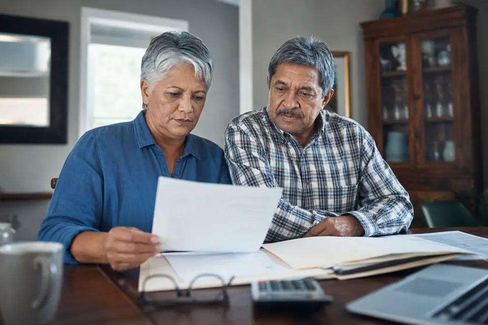 Retired couple reviewing a letter and old tax returns at their table