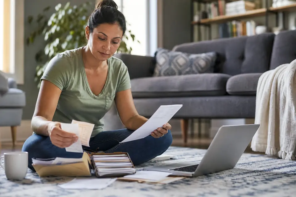 Woman sorting receipts and statements into folders on her living room floor